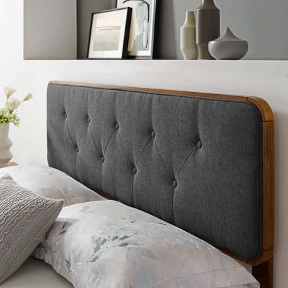 Black tufted fabric headboard with wooden frame and rounded edges, paired with floral bed linens.