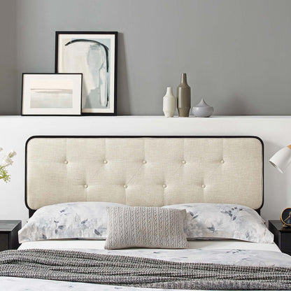 Brown tufted headboard with black trim above a bed with floral bedding, gray knit throw, abstract art and vases on shelf.