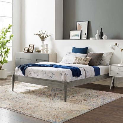 Gray wood queen platform bed frame with floral bedding and blue accents; contemporary bedroom with dresser, rug, and plant.