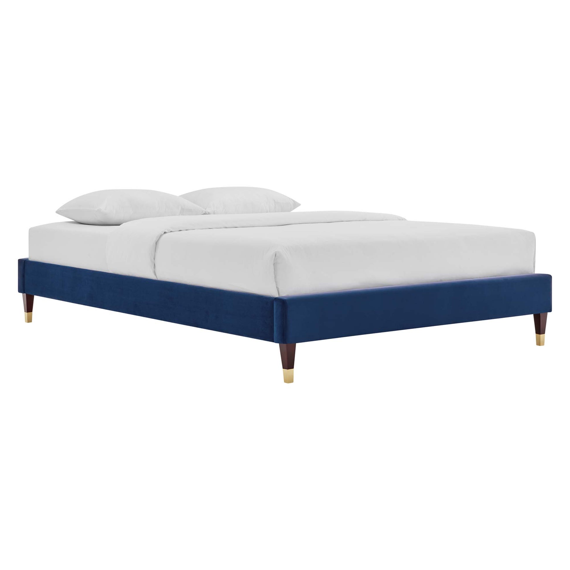 Navy blue velvet platform bed with low frame, tapered wooden legs and brass caps, white bedding.