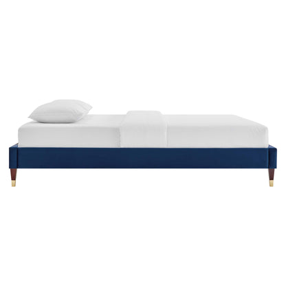 Navy blue upholstered platform bed frame with brass-tipped legs and a white mattress.