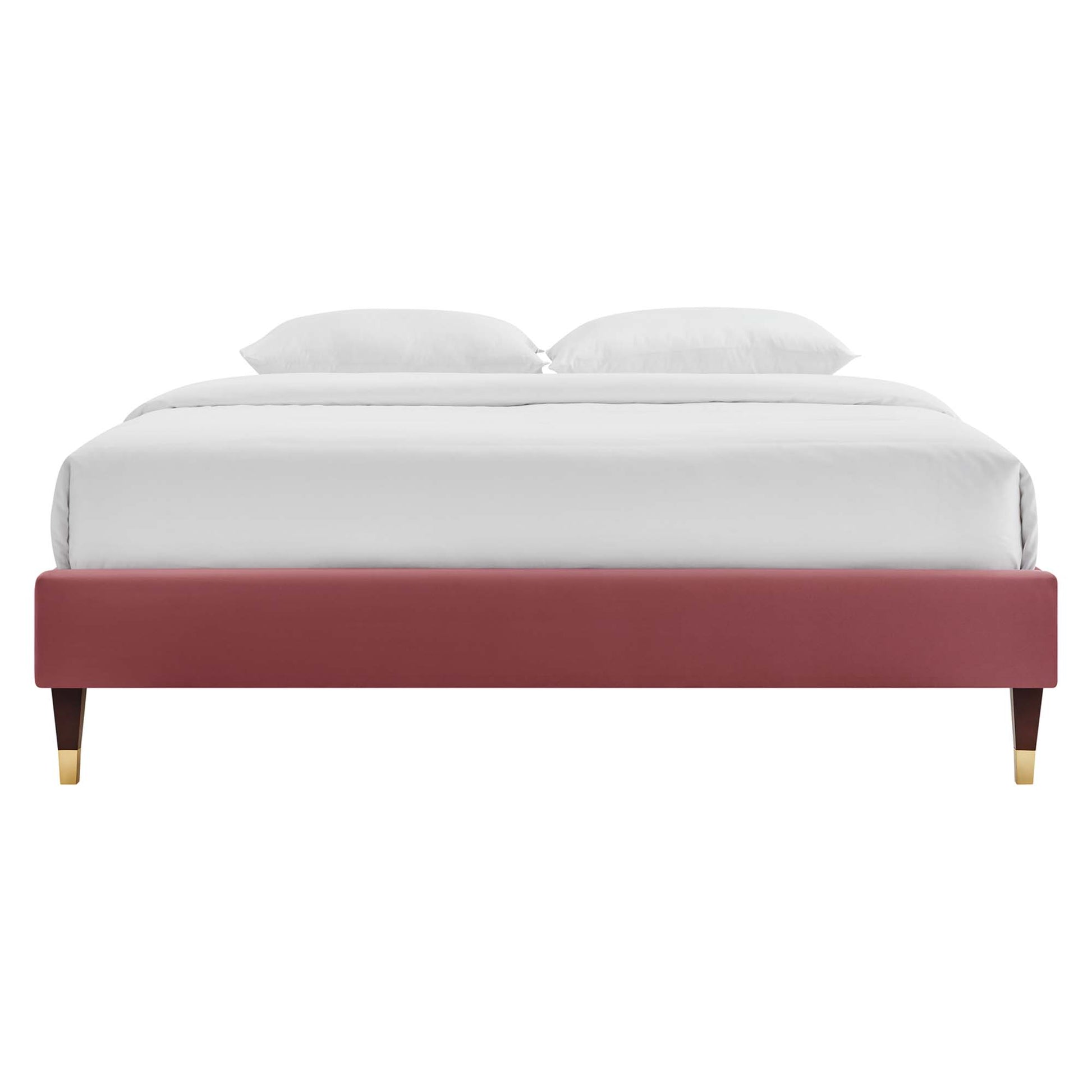 Maroon upholstered platform bed with gold-tipped wooden legs, white bedding and two pillows.