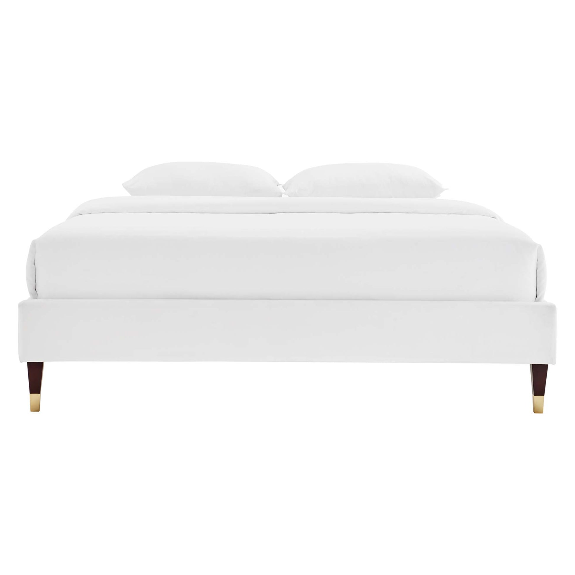 White upholstered platform bed frame with clean lines, white bedding and two pillows, tapered wooden legs with brass caps.