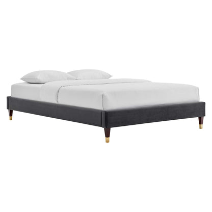 Charcoal gray upholstered king platform bed frame in modern style with white bedding and tapered legs with gold caps.