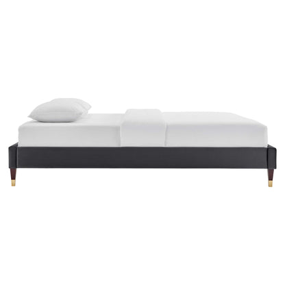 Charcoal gray upholstered platform bed with gold-tipped legs and white bedding.