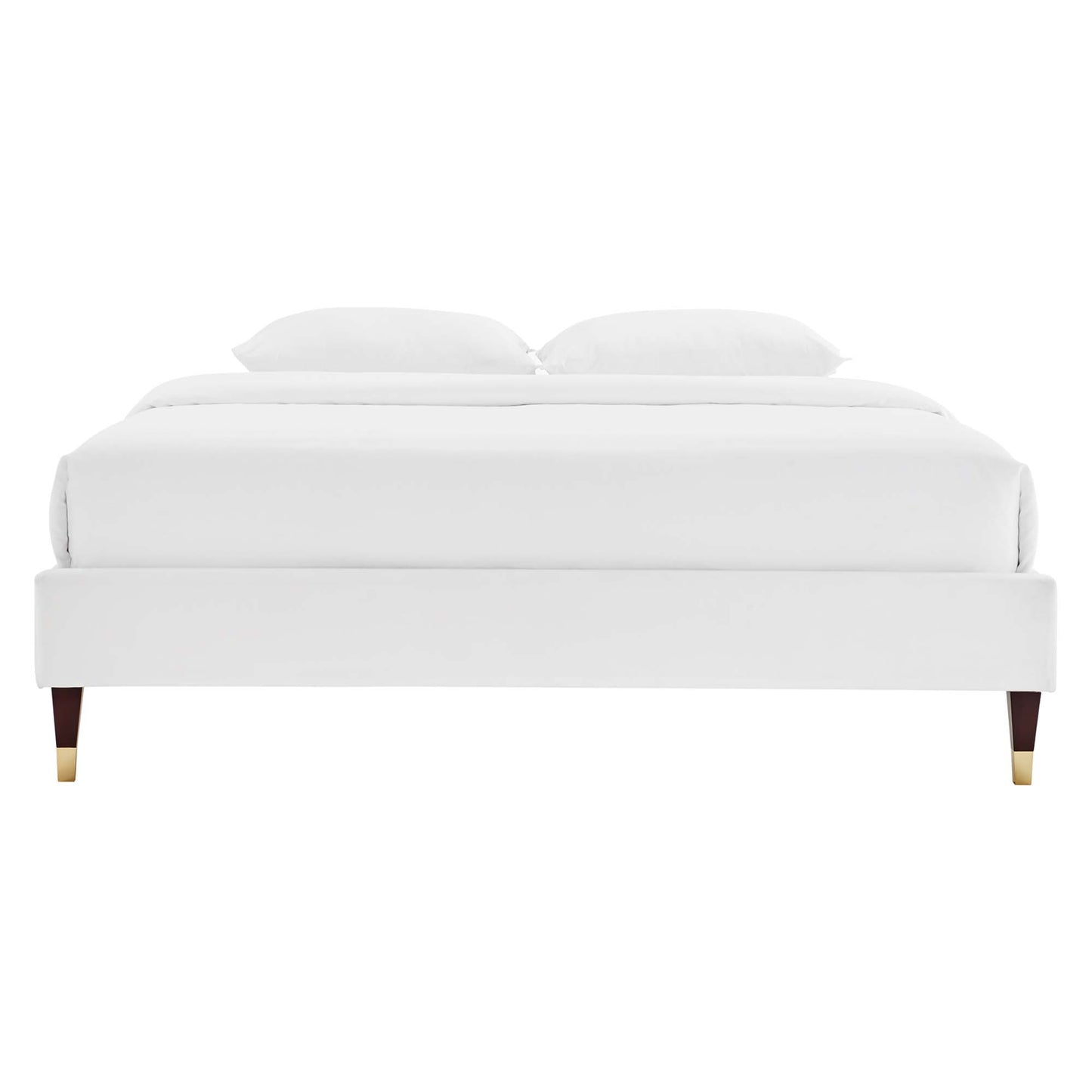 White upholstered platform bed with low profile frame & white bedding, dark wood legs with brass caps.
