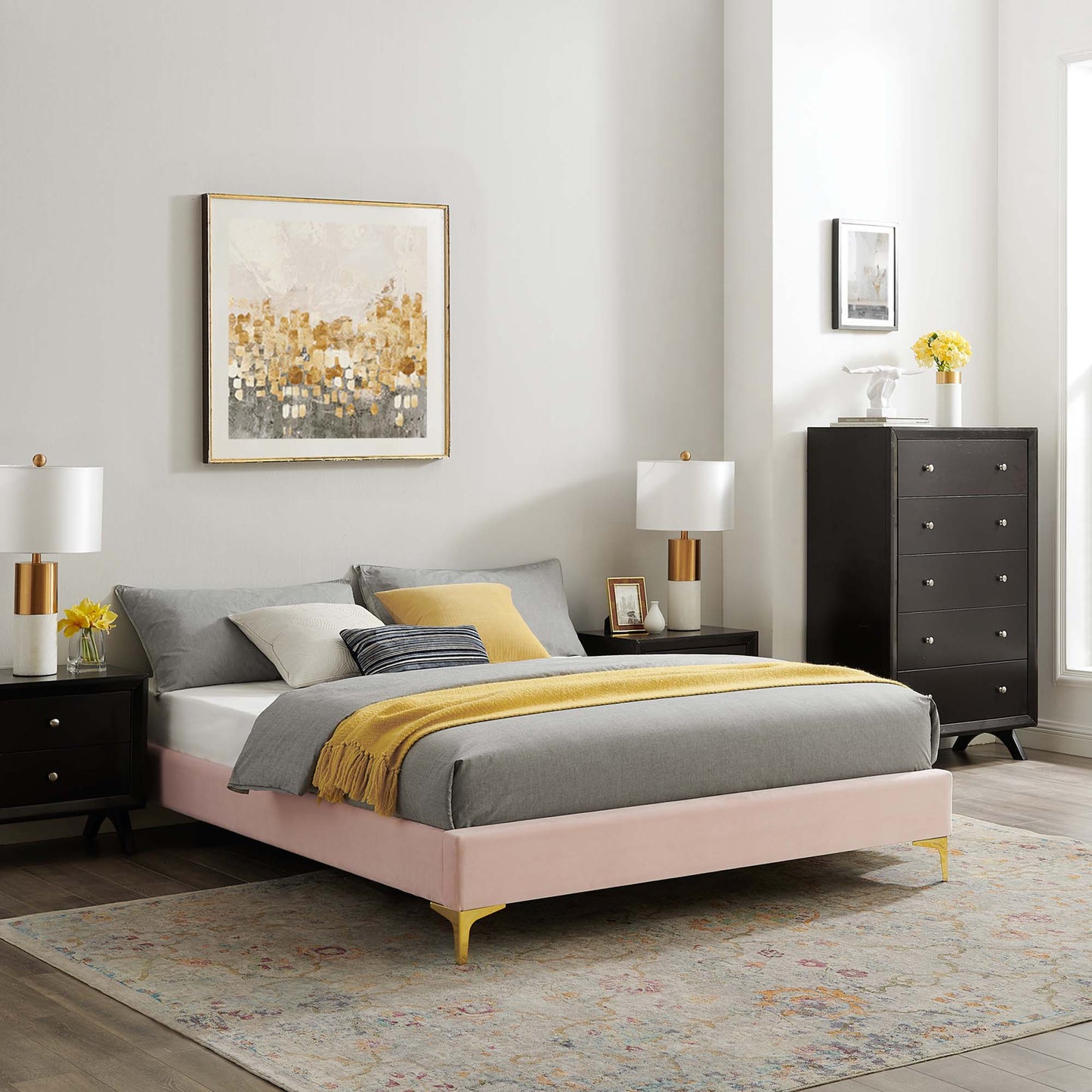 Red upholstered queen bed frame with gray bedding and a yellow throw, black nightstands, gold-accent lamps, and a tall dresser.