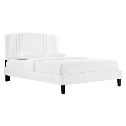 White upholstered platform bed with tall vertical-channel headboard, cushioned frame, black tapered legs, and two pillows.