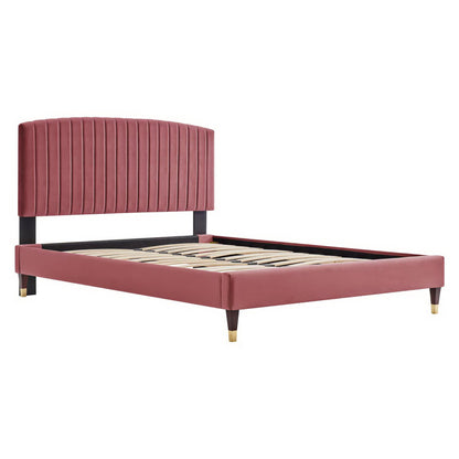Dusty-rose velvet platform bed with tall vertical-channel headboard, black legs with brass caps, slatted base.