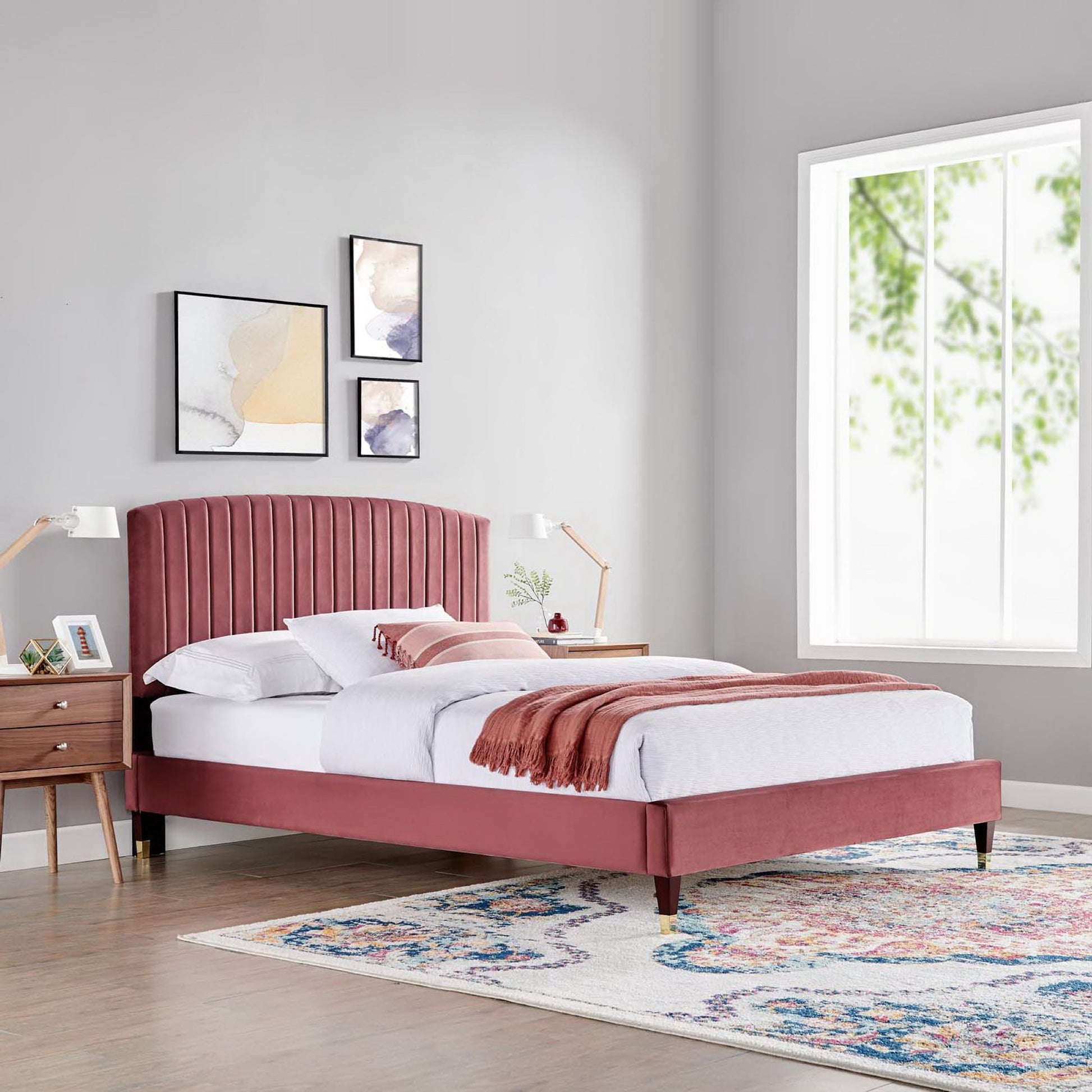 Red velvet bed with tall tufted headboard, white bedding, rust throw, mid-century nightstands, abstract art, colorful rug.