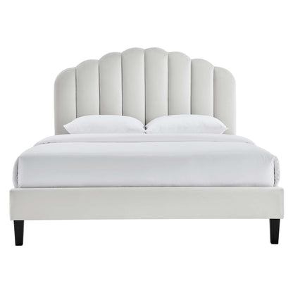 Gray upholstered queen platform bed with a tall scalloped headboard, white bedding, & black tapered legs.