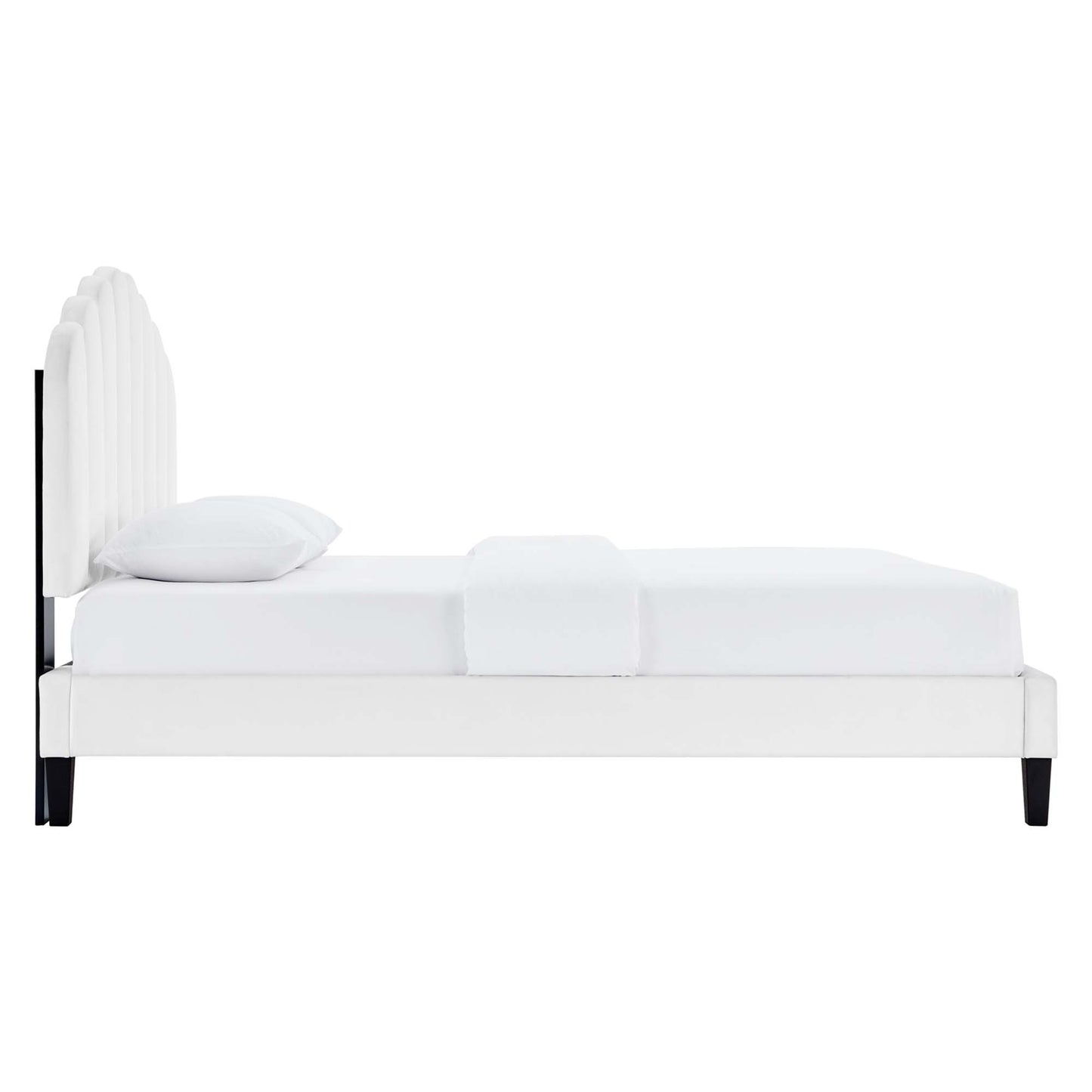 White upholstered platform bed with curved slat headboard, crisp bedding and dark tapered legs.