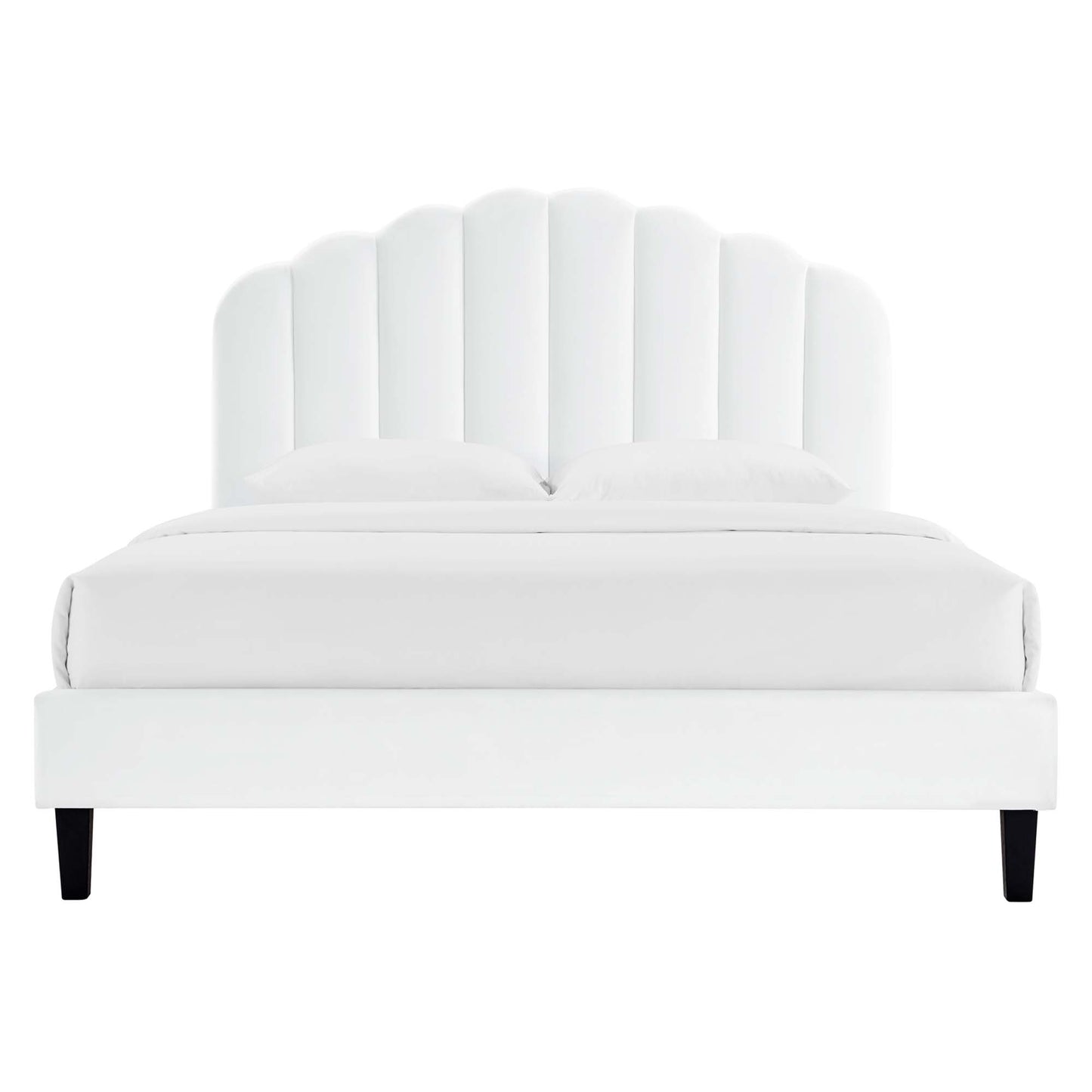 White upholstered platform bed with a scalloped curved headboard, two pillows, and black tapered legs.