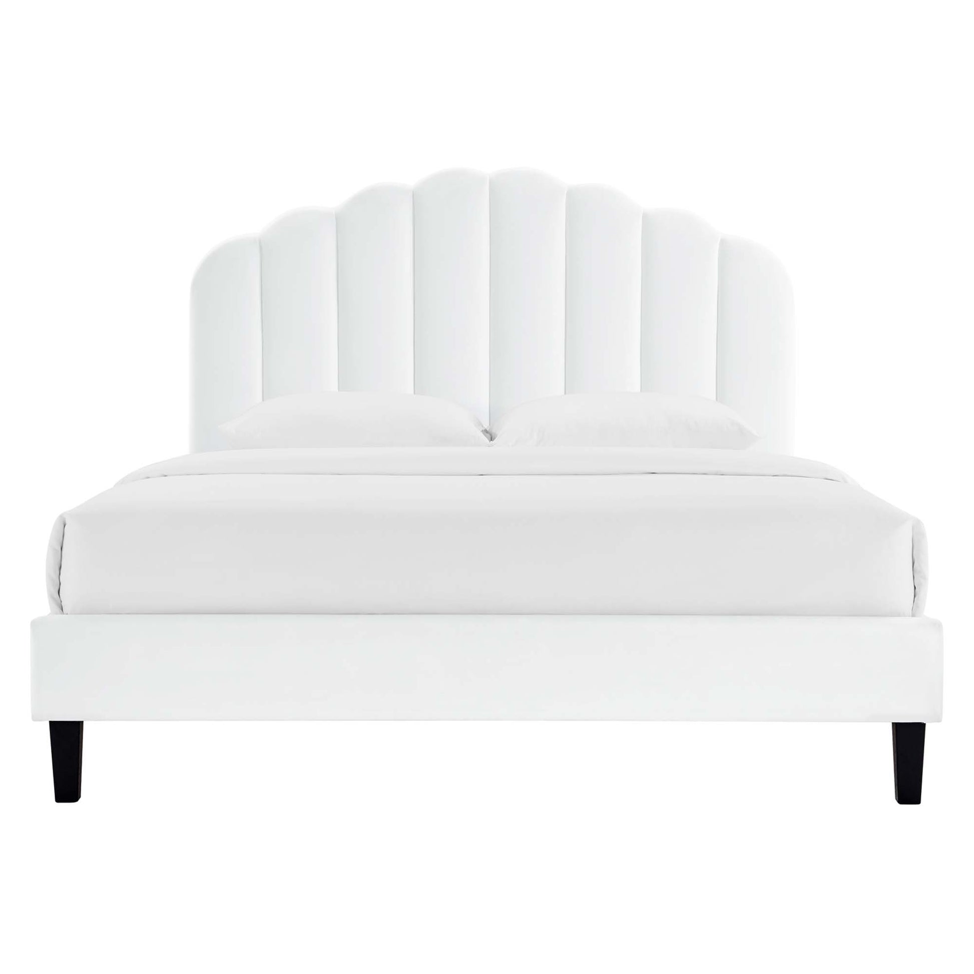 White upholstered platform bed with a scalloped curved headboard, two pillows, and black tapered legs.