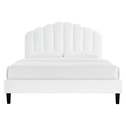 White upholstered platform bed with a scalloped curved headboard, two pillows, and black tapered legs.