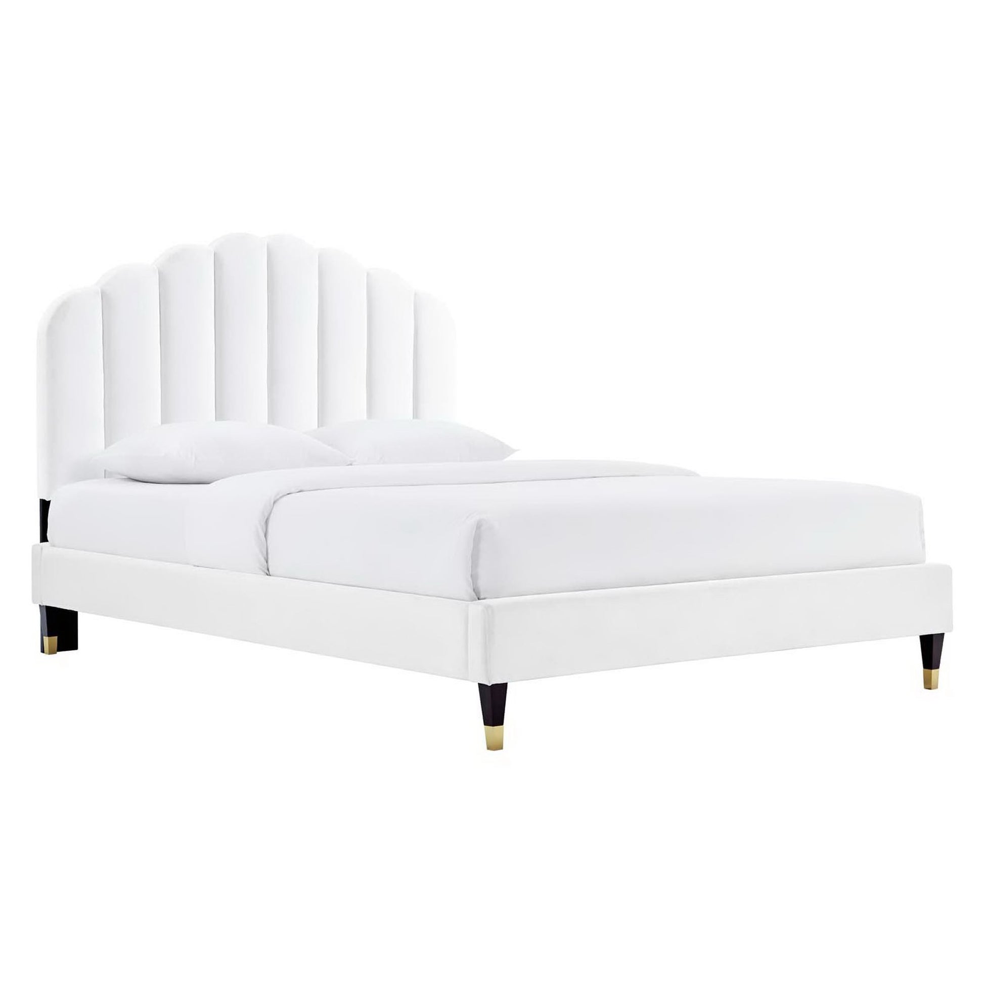 White upholstered bed with tall curved panel headboard, white bedding, and gold-tipped legs.