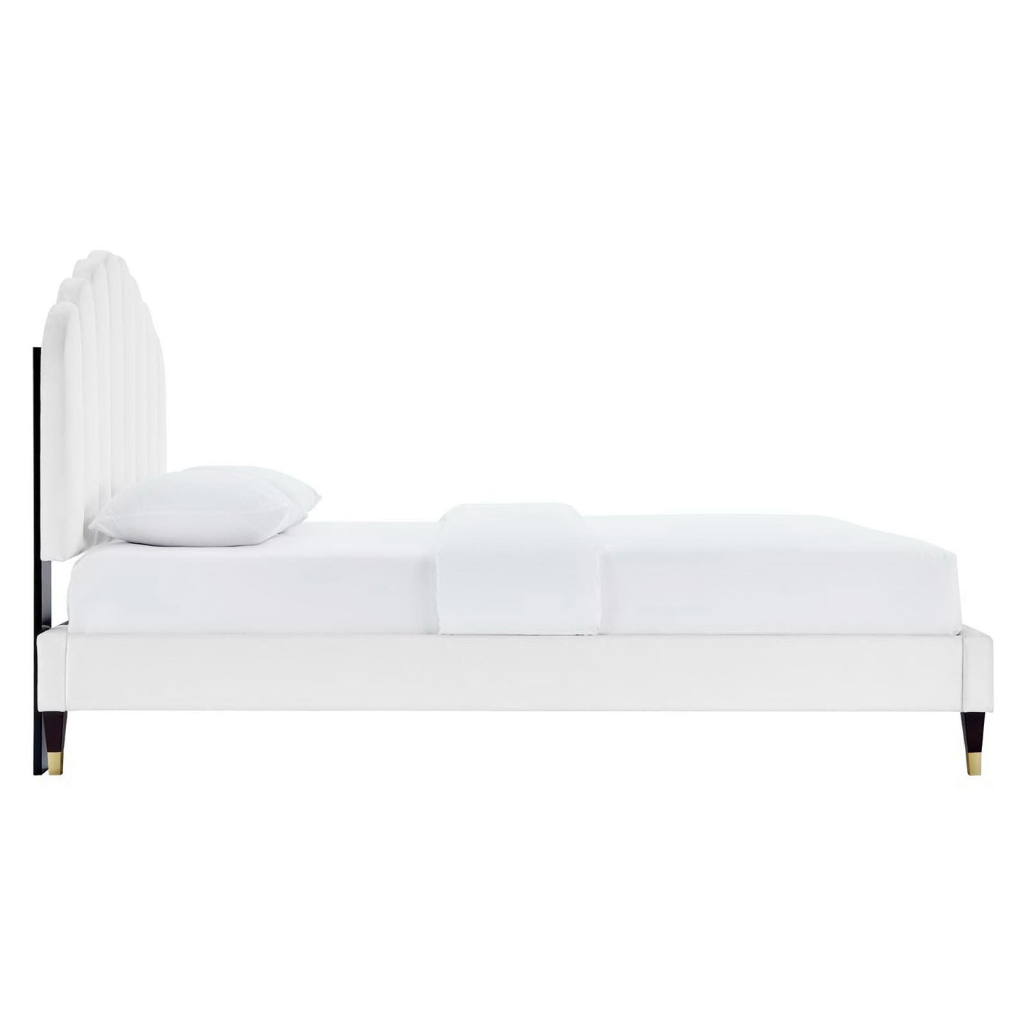 White upholstered platform bed with tall curved headboard, white bedding, and dark tapered legs with brass caps.