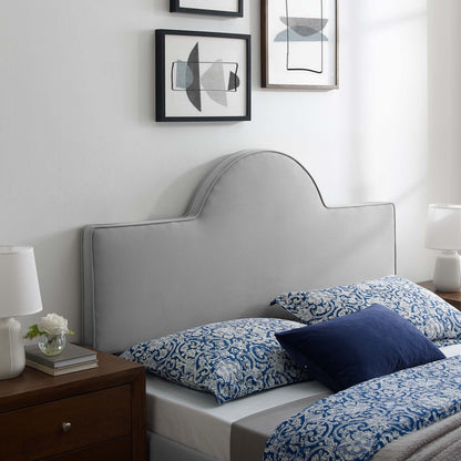 Light gray upholstered headboard with curved top, blue damask bedding, navy pillow, wooden nightstands and lamps