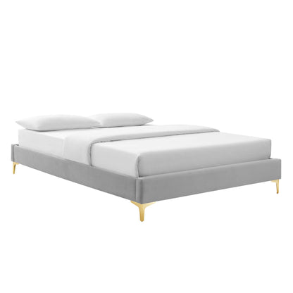 Light gray upholstered platform bed with low profile frame, white bedding, two pillows & gold tapered legs.