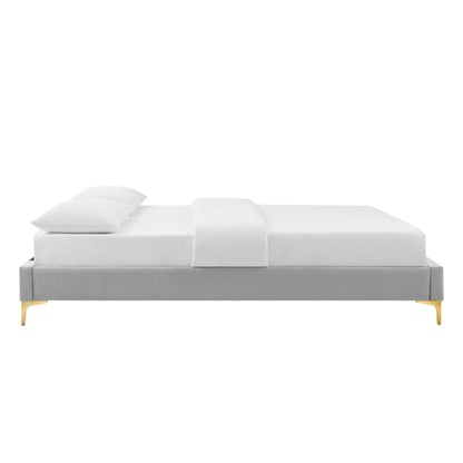 Light gray fabric platform bed with clean lines, white bedding and pillows, and gold-tinted tapered legs.