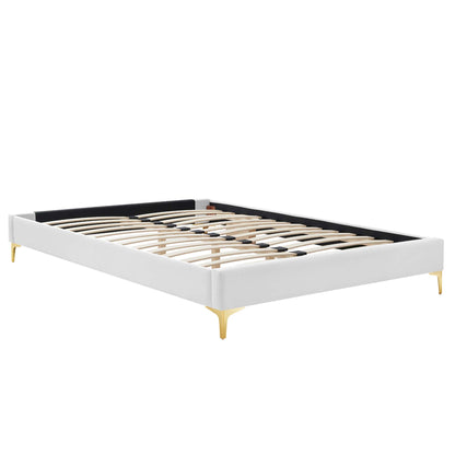 White upholstered platform bed frame with wooden slats, black inner back panel and gold tapered legs.