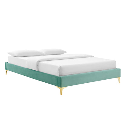 Mint green upholstered platform bed with gold-tone legs, modern low-profile design, white mattress and pillows.