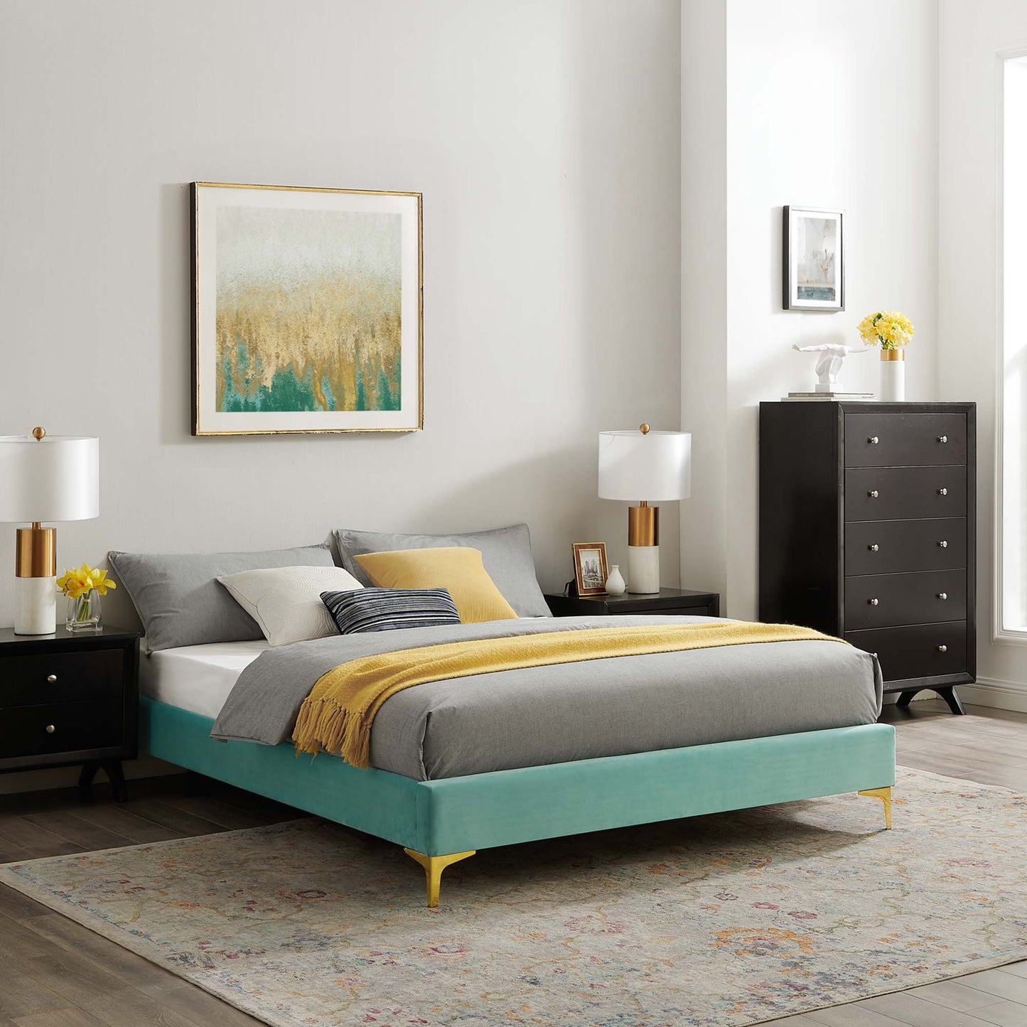 Mint velvet king bed frame with gold legs, grey bedding and a yellow throw, black nightstands, lamps, and abstract art.