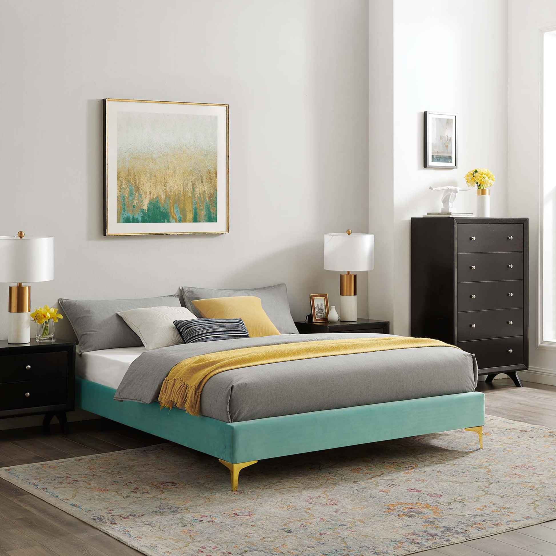 Mint velvet king bed frame with gold legs, grey bedding and a yellow throw, black nightstands, lamps, and abstract art.