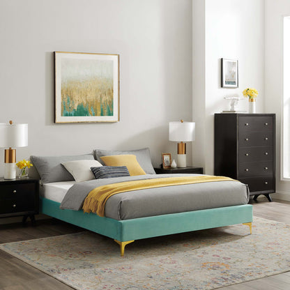 Mint velvet king bed frame with gold legs, grey bedding and a yellow throw, black nightstands, lamps, and abstract art.