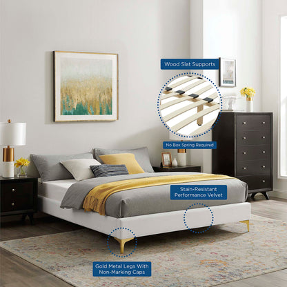 White upholstered bed frame with metal legs, gray bedding and a yellow throw; wood slat supports; no box spring needed.
