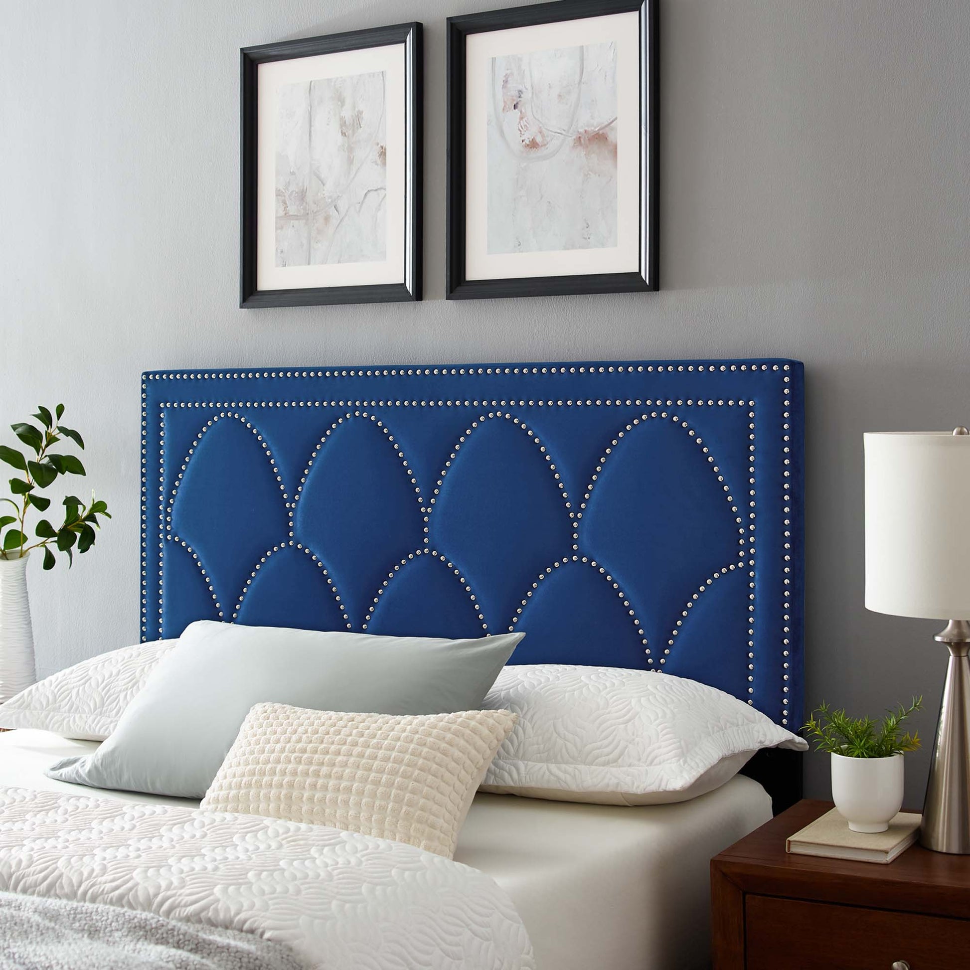 Navy blue velvet upholstered headboard with scalloped arches and silver nailhead trim, modern glam bed centerpiece.