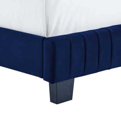 Navy blue velvet bed frame corner with vertical channel tufting and a dark square wooden leg.