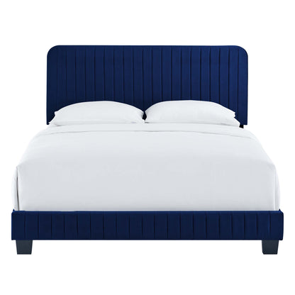 Navy blue velvet upholstered king bed with a tall, vertical-channel headboard and matching footboard, white bedding.