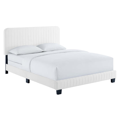 White velvet upholstered king bed with a tall channel-tufted headboard, dark cube legs and white bedding.