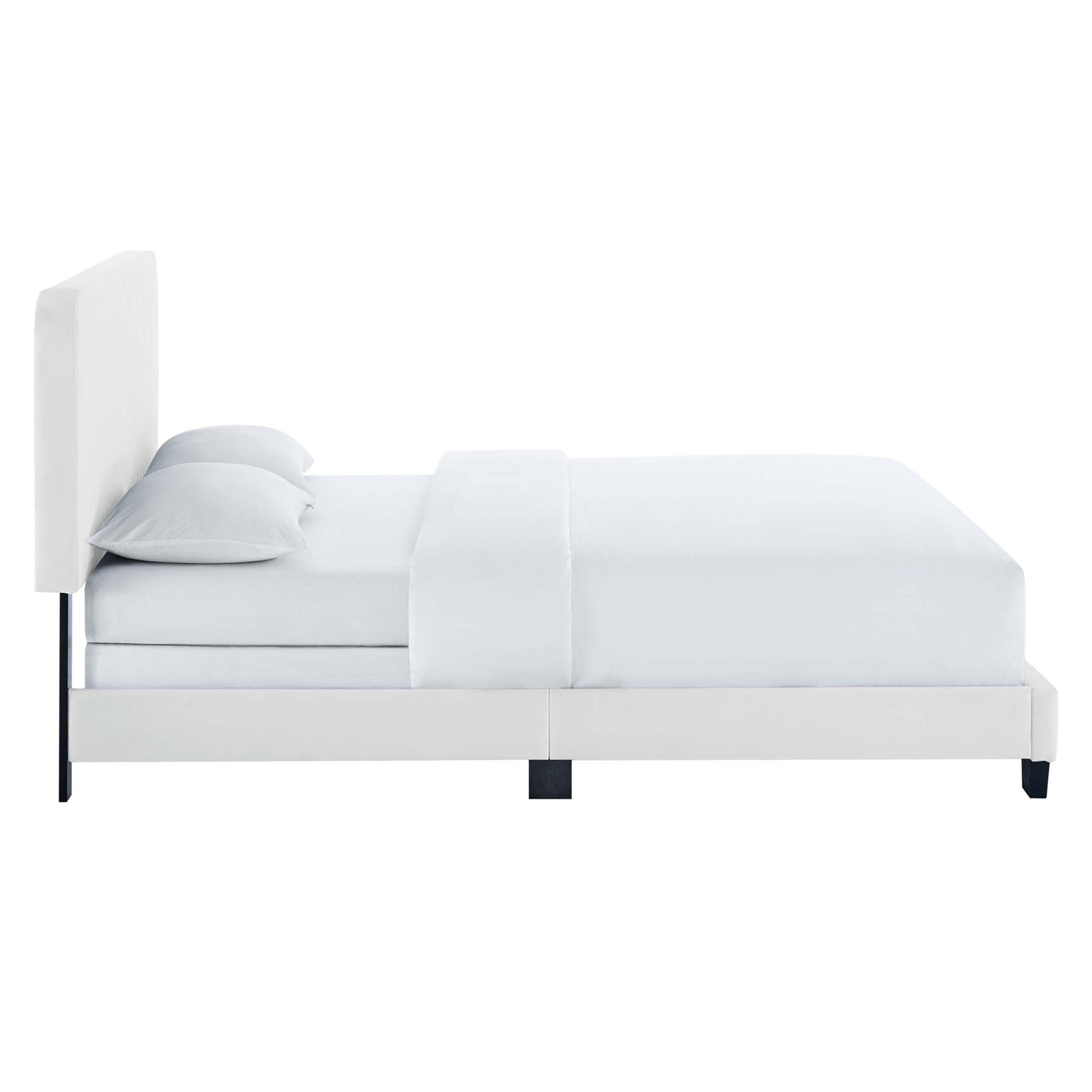 White upholstered platform bed with tall padded headboard, white bedding and black low legs.