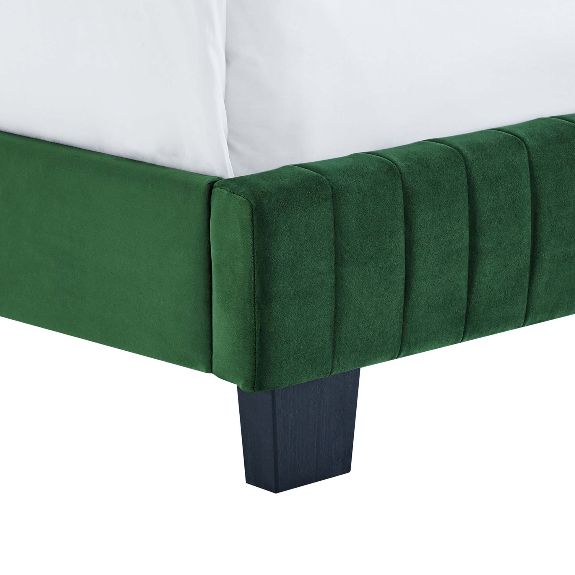 Emerald green velvet bed with channel tufted headboard, white pillows, dark square wood legs.