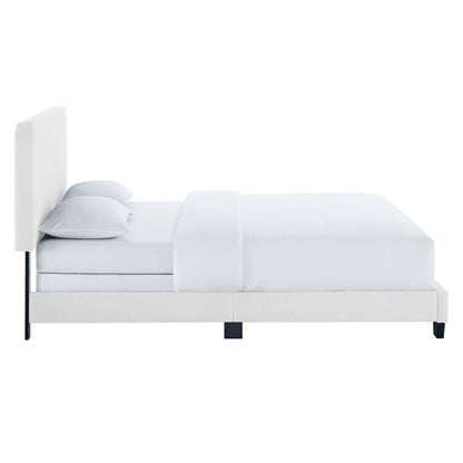 White upholstered platform bed with tall padded headboard, minimalist design, white sheets and pillows.