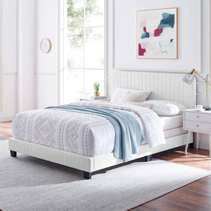 White tufted upholstered bed with a tall headboard, geometric duvet, pale blue throw, in a bright airy bedroom with abstract art.