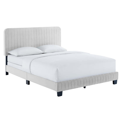 Light gray upholstered bed with tall vertical-stitched headboard, low platform frame, and white bedding.