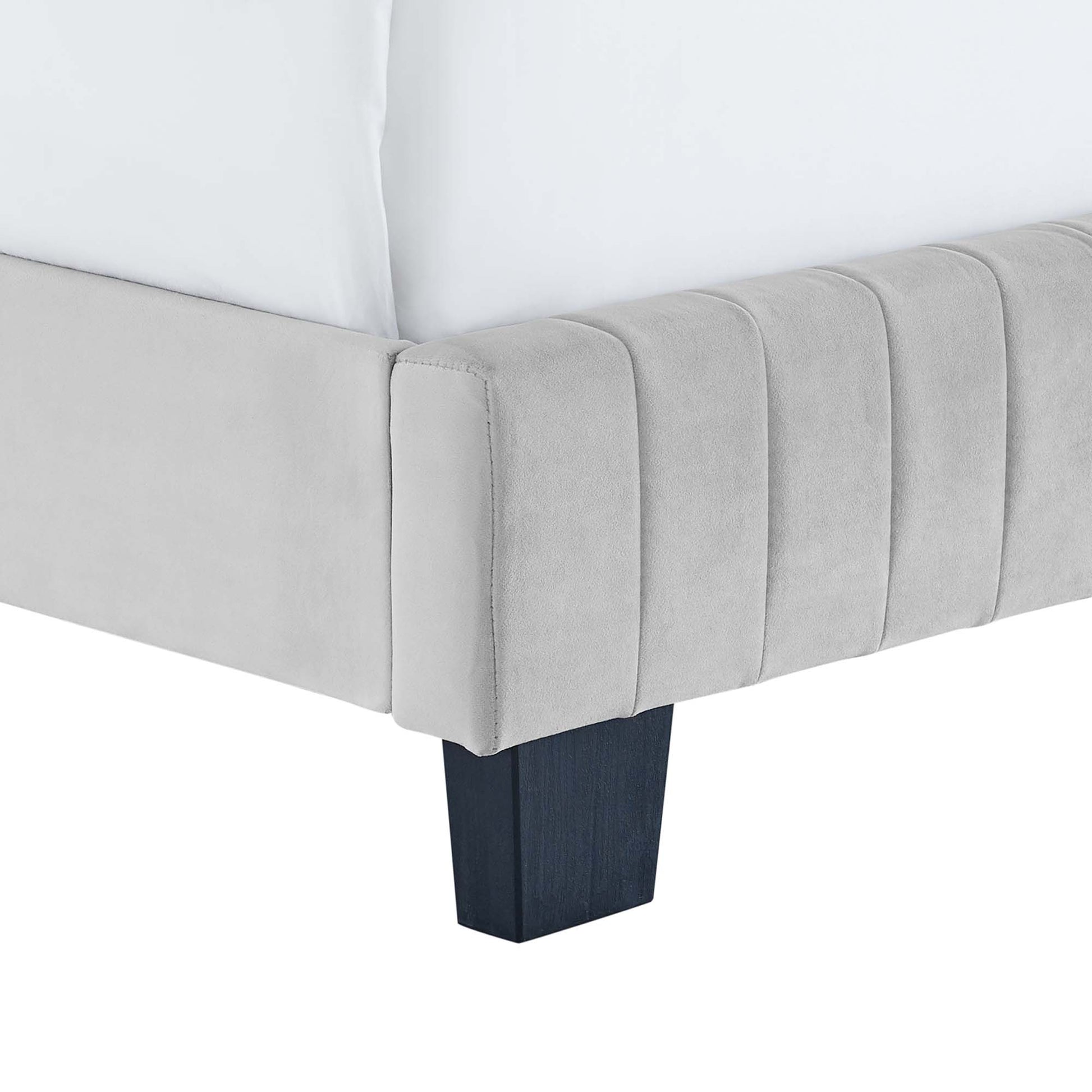 Corner view of a light gray velvet full bed with vertical channel tufting and dark square wood legs.