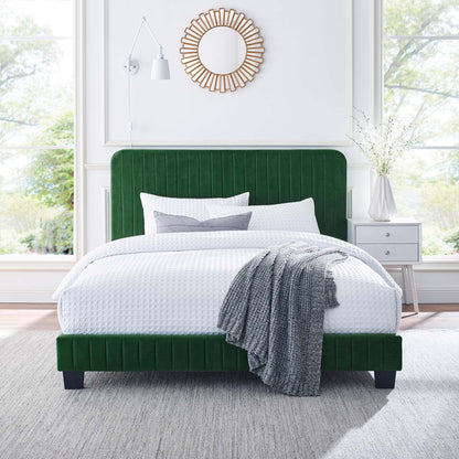 Emerald green velvet bed with tufted headboard, white textured bedding, gray knit throw, sunburst mirror above.