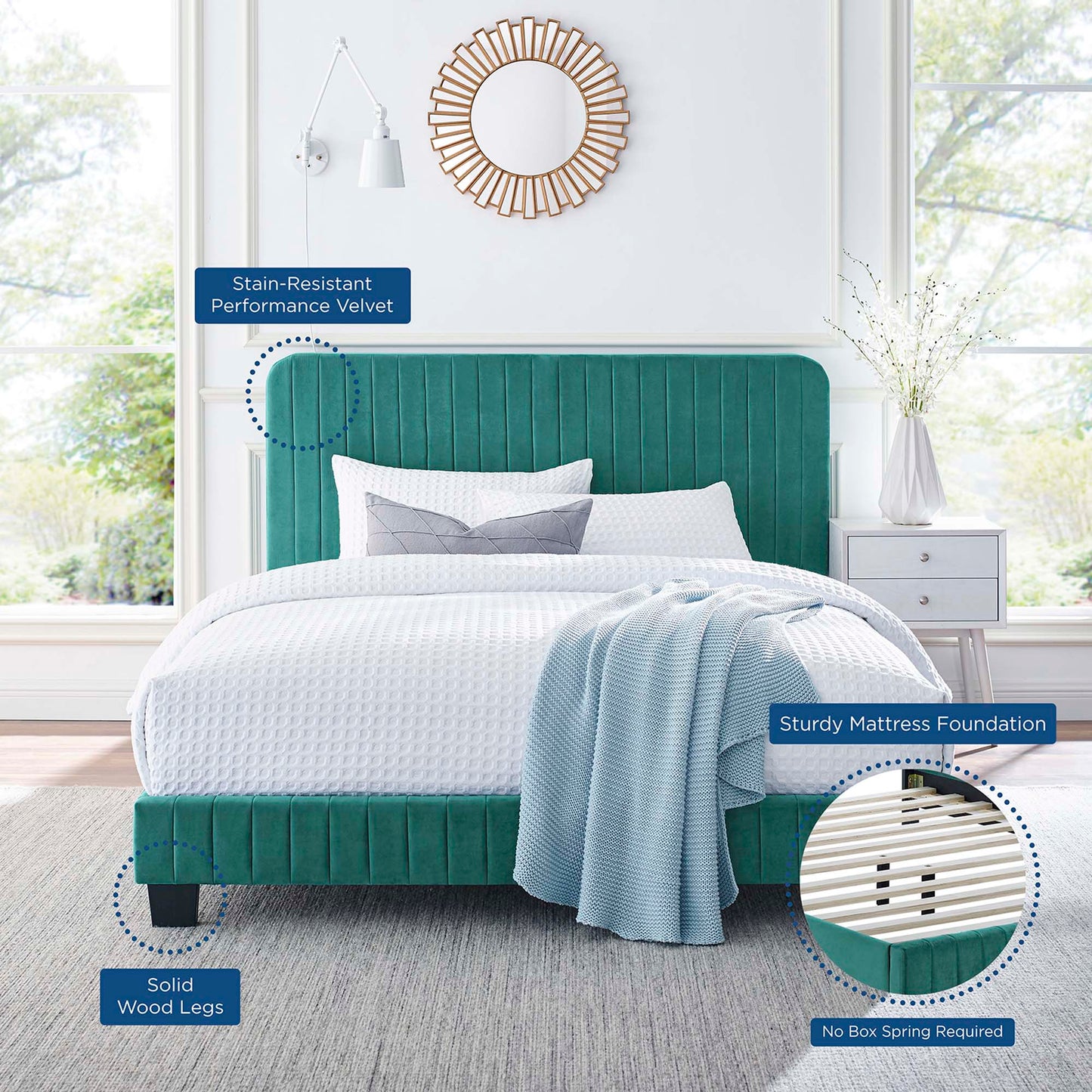 Teal velvet king platform bed with channel-tufted headboard in a bright modern bedroom, white bedding and a light blue throw, with a sunburst mirror in the background.