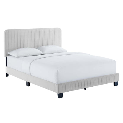 Light gray upholstered bed with tall vertical-channel tufted headboard, low platform footboard, and dark legs.