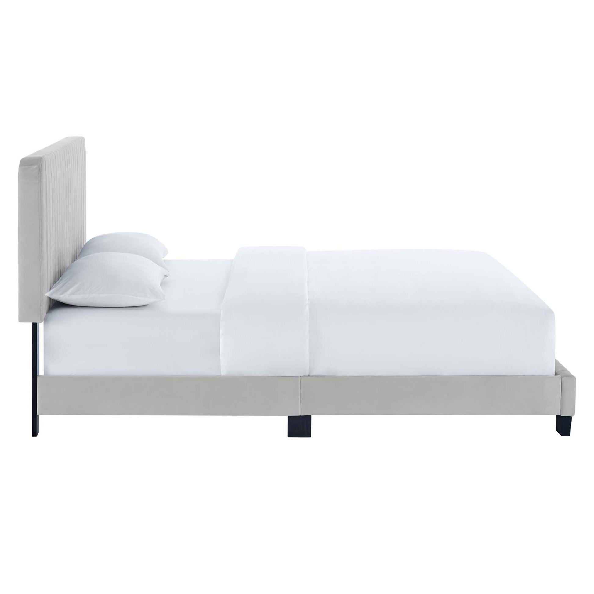 Gray upholstered platform bed with tall padded headboard, white bedding and pillows, slim black legs.