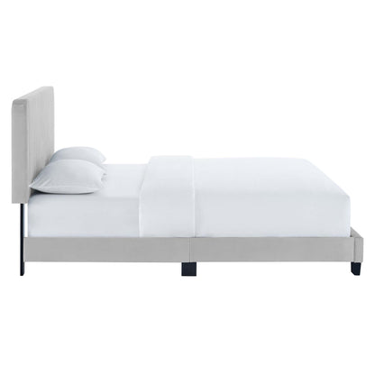 Gray upholstered platform bed with tall padded headboard, white bedding and pillows, slim black legs.