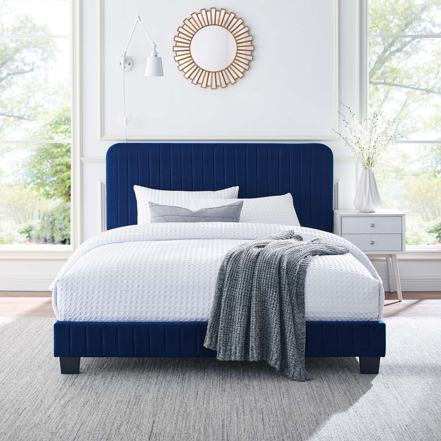 Navy blue upholstered bed with tall channel-tufted headboard, white textured bedding and gray throw; contemporary bedroom.