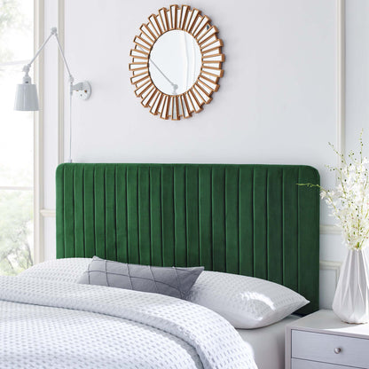 Emerald velvet headboard with vertical channels, white bedding, gray pillow, sunburst mirror, white nightstand with vase.