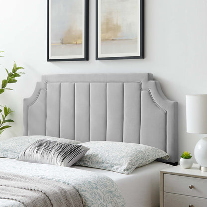 Grey padded upholstered headboard with winged edges and vertical channel stitching, feather-gray bedding and abstract art.
