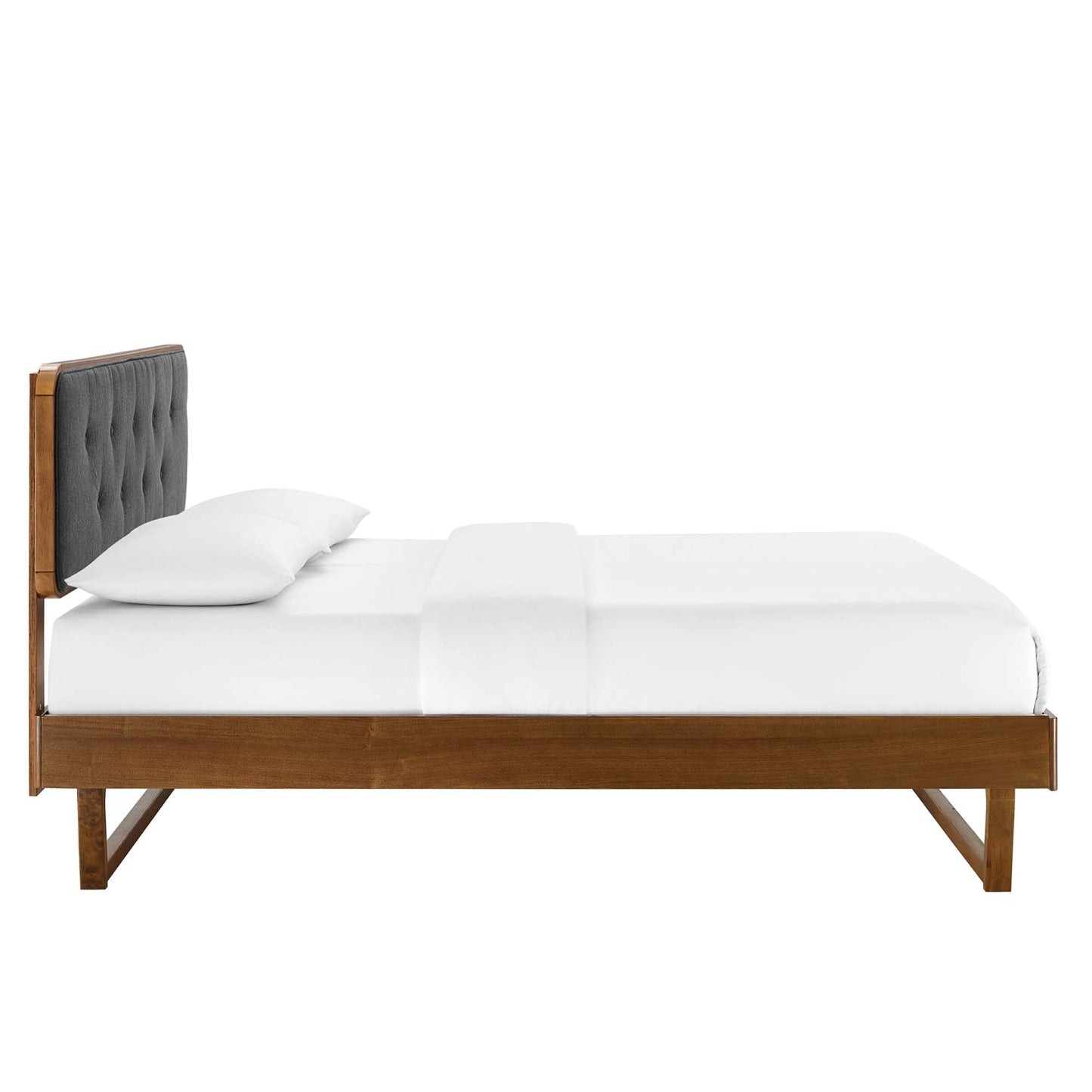 Walnut wood queen platform bed with angular frame and crisp white bedding.