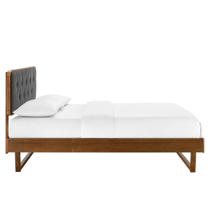 Walnut wood queen platform bed with angular frame and crisp white bedding.